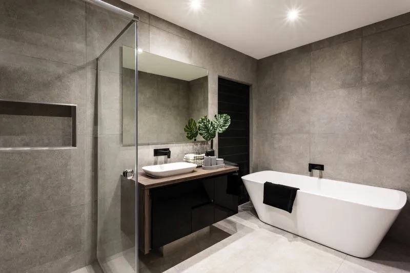 A bathroom with a long bathtub, flowers, and brown cabinets