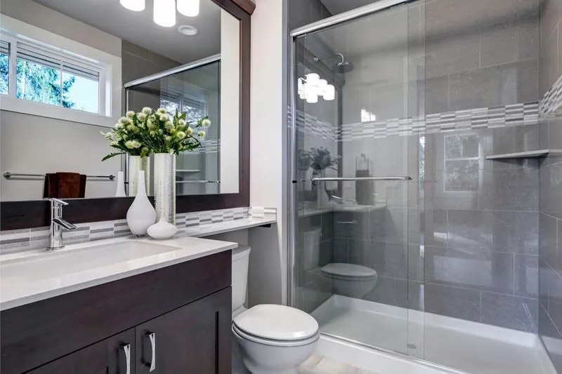 Bathroom with full length shower, flowers, and brown cabinets