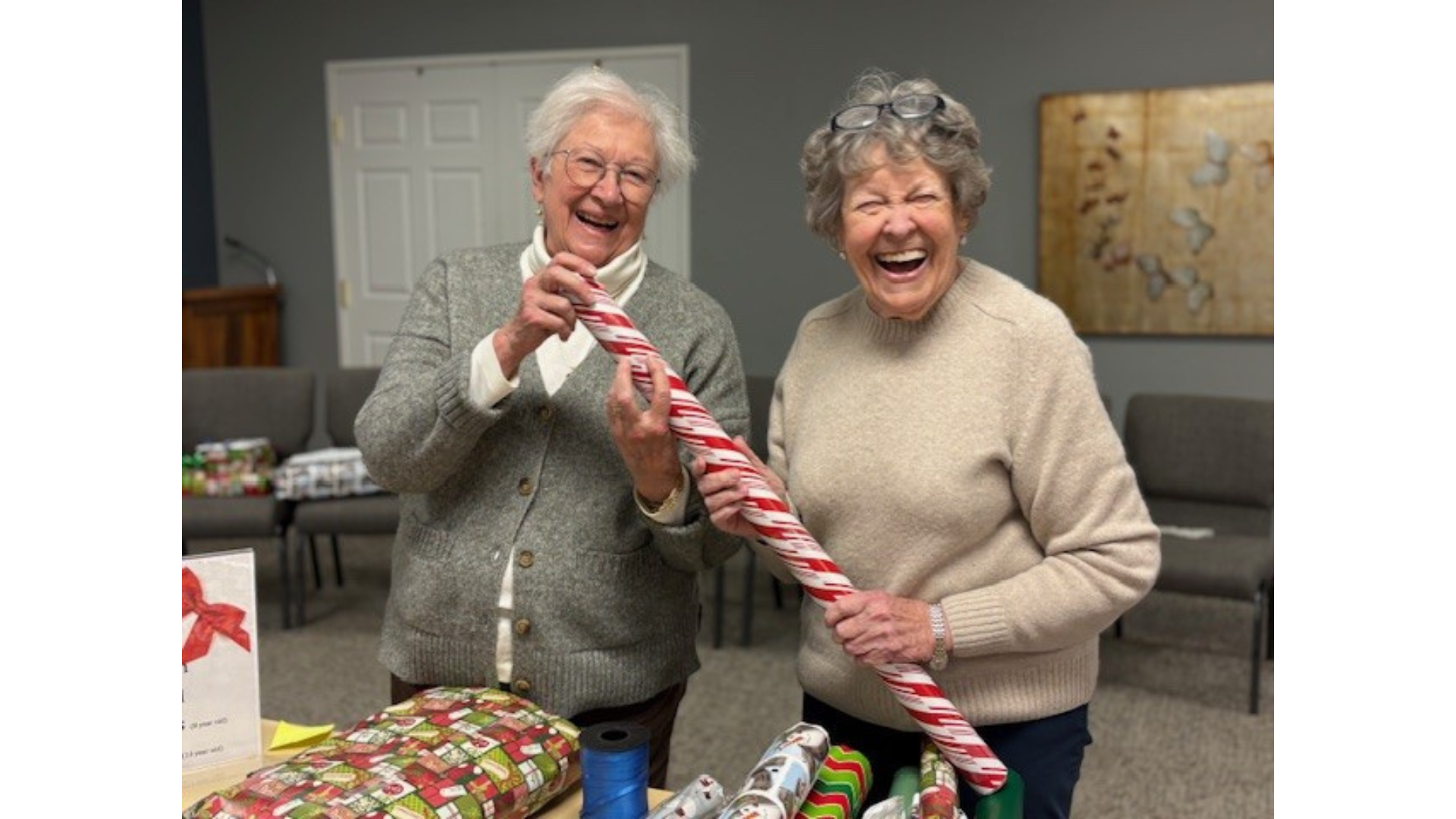 Two residents holding wrapping paper at the pen pal community wrapping party
