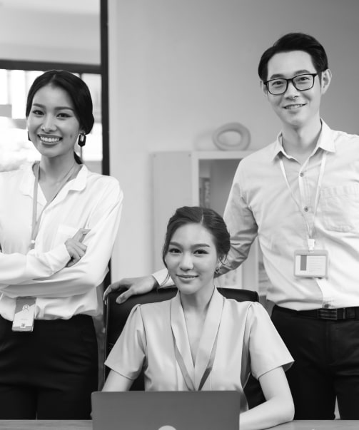 Three smiling team members with ID badges, posing together in an office setting.