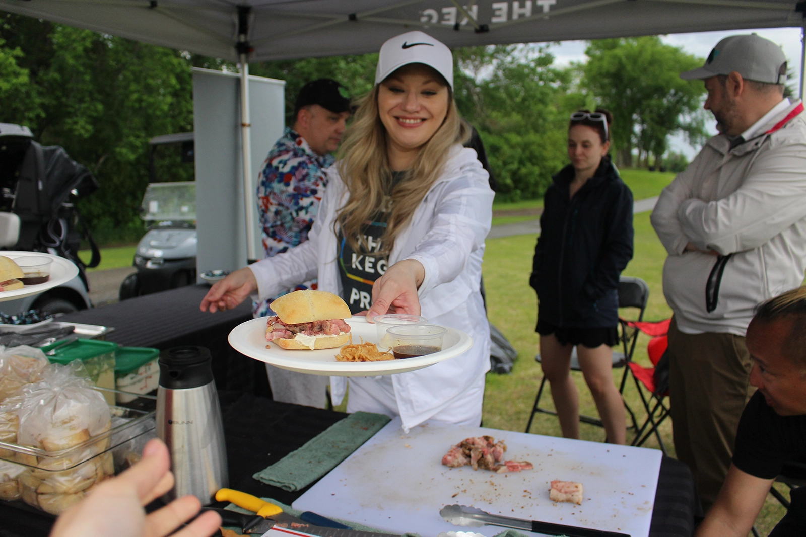 Excel Society member handing out a plate of food during an outdoor event.