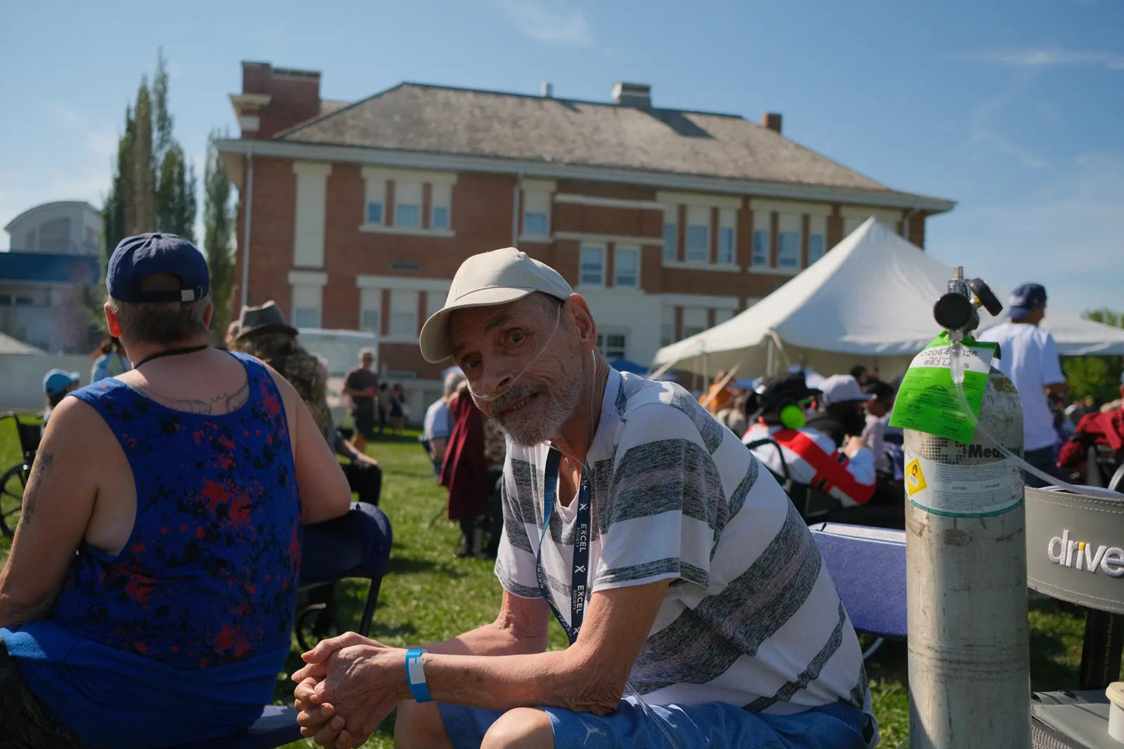 Photo of a man leaning over his knees and smiling at the camera.