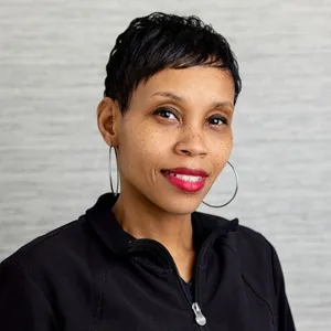 Portrait of Dana, patient coordinator, wearing a black zip-up jacket against a light gray background.