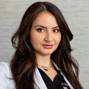 Portrait of Dr Catherine El Hadi in a white coat, looking confidently at the camera with a neutral expression.
