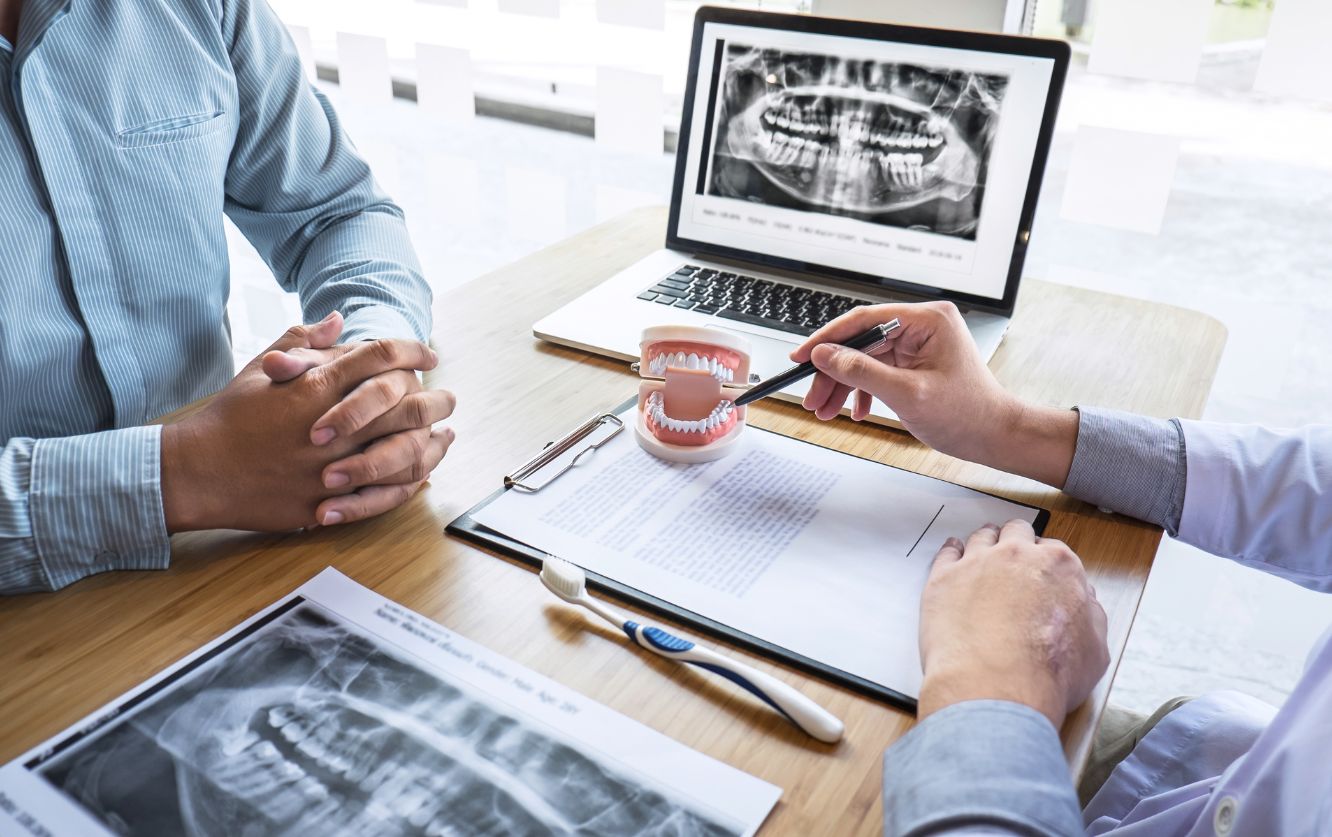 Dentist showing X-ray images to a female patient during a consultation, pointing to specific areas of concern
