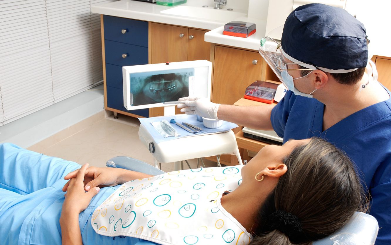Dentist reviewing digital 3D dental scan on a computer monitor while discussing treatment plan with a patient