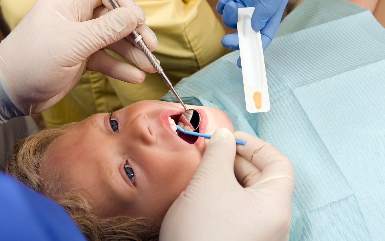 Female patient lying back as the dentist works in her mouth using suction during a routine dental procedure