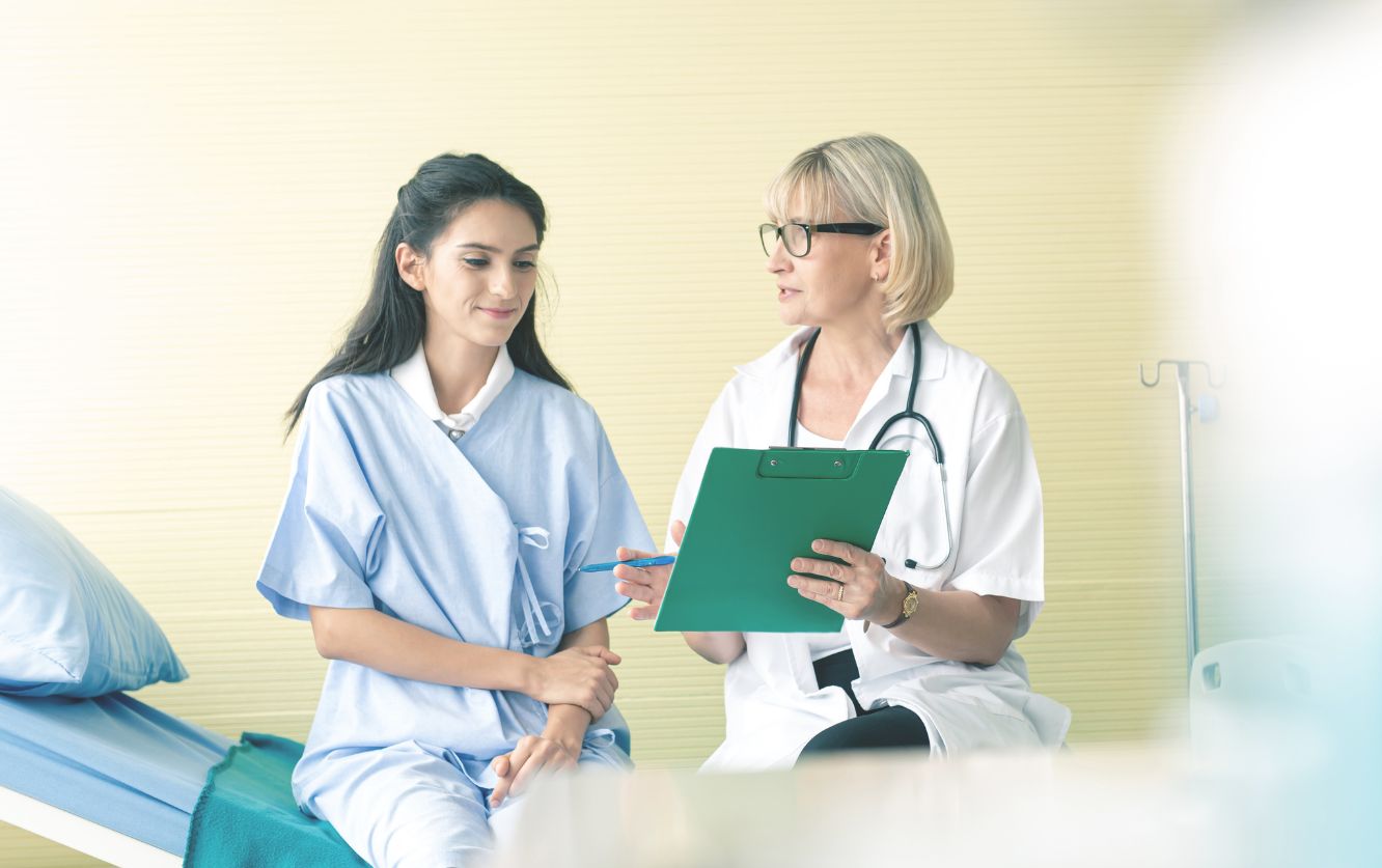 Two female dentists discussing a case with documents in hand, seated in a dental office wearing lab coats