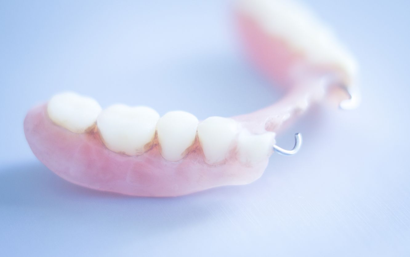 Set of lower dentures resting on a reflective surface, showcasing the acrylic pink gum base and evenly shaped artificial teeth intended for edentulous patients