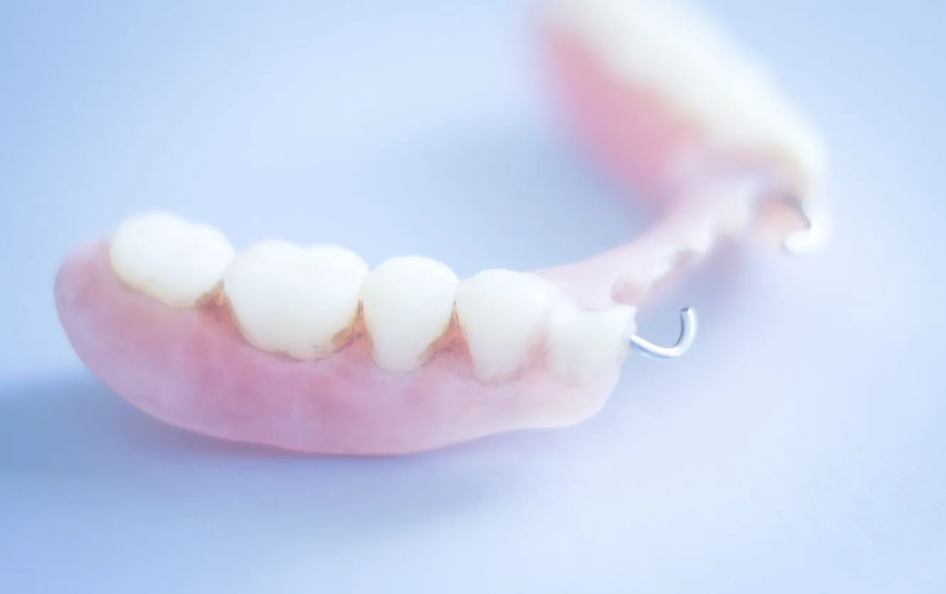 Set of lower dentures resting on a reflective surface, showcasing the acrylic pink gum base and evenly shaped artificial teeth intended for edentulous patients
