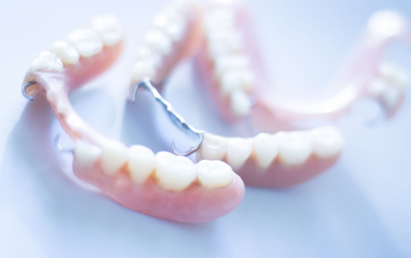 Removable dental prosthetics displayed on a white tray, featuring full upper dentures with translucent edges designed to mimic natural gum contours