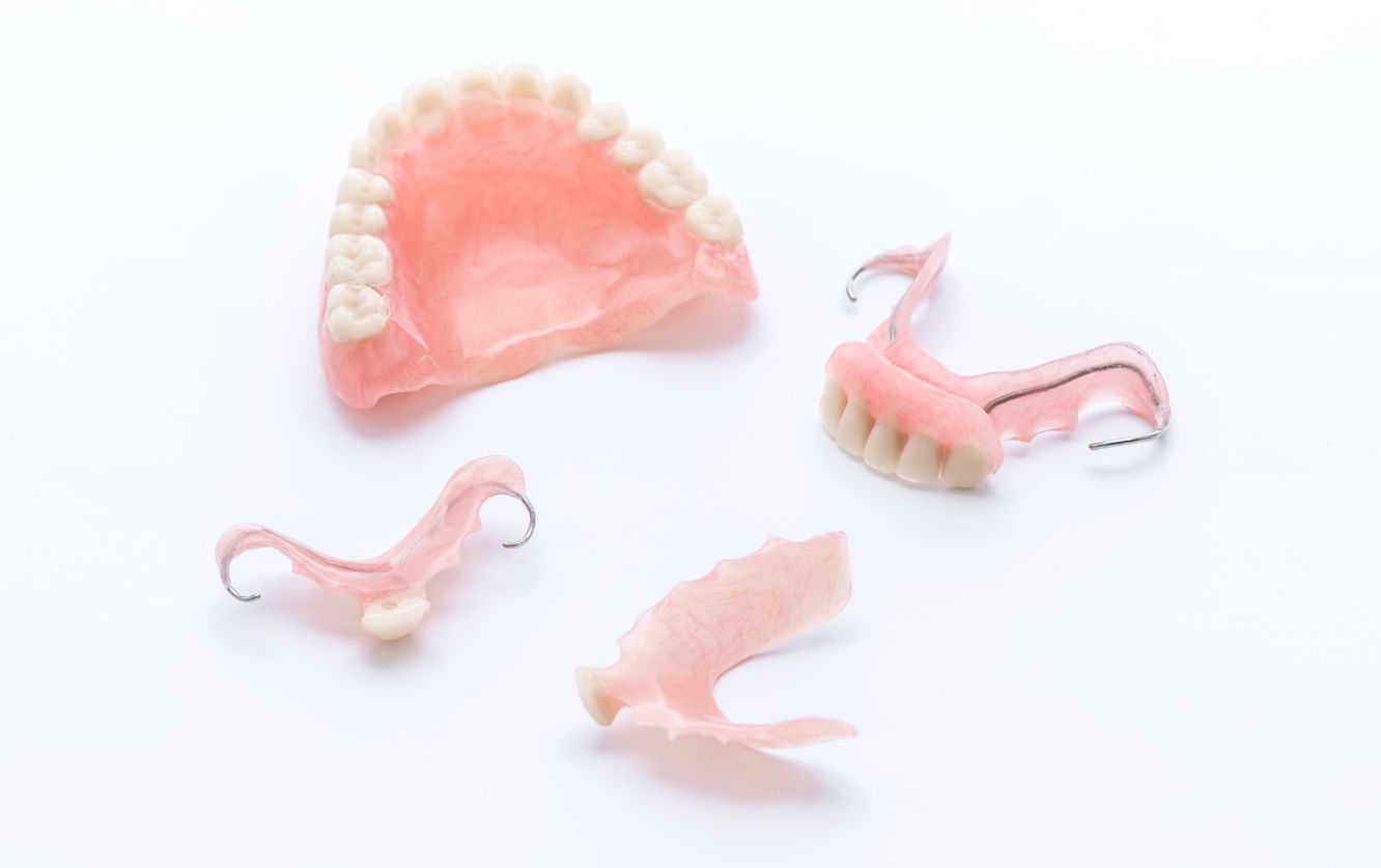Collection of pink acrylic denture pieces in varying sizes, including full and partial prosthetics for upper and lower jaws, arranged for dental treatment planning