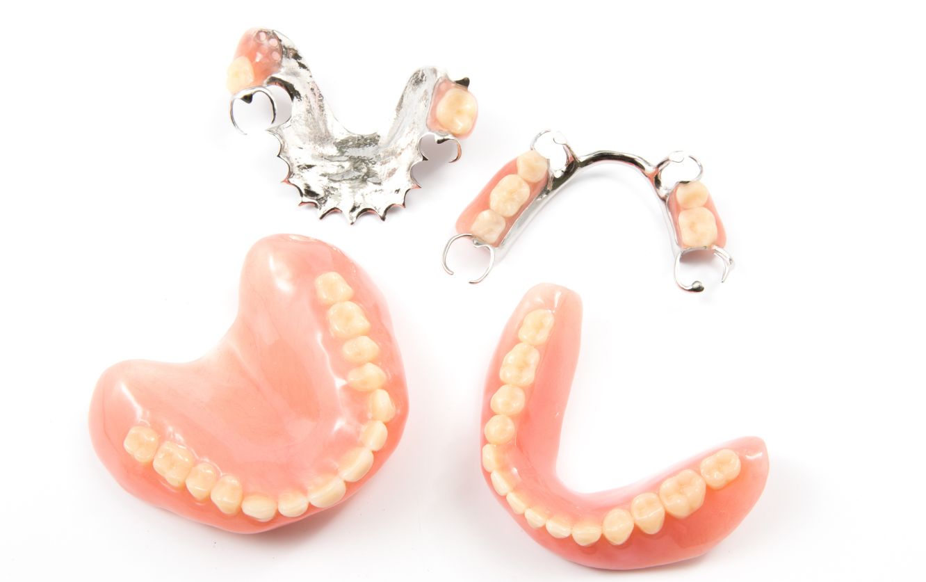 Set of upper and lower removable dentures with acrylic gum base and porcelain teeth displayed on a white background for prosthodontic consultation