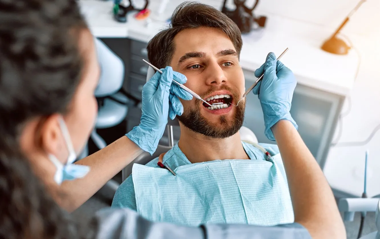 Male patient receiving a general dental checkup from a dentist wearing blue gloves at Fortson Dentistry in Lathrup Village, MI