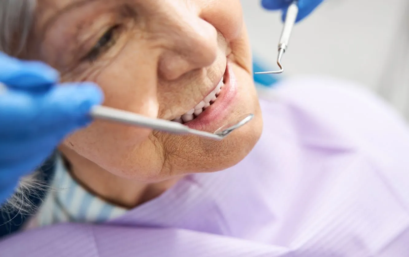Senior woman receiving gentle dental exam at Fortson Dentistry in Lathrup Village, MI, showing healthy teeth during oral checkup with professional tools and gloved hands in a caring dental environment