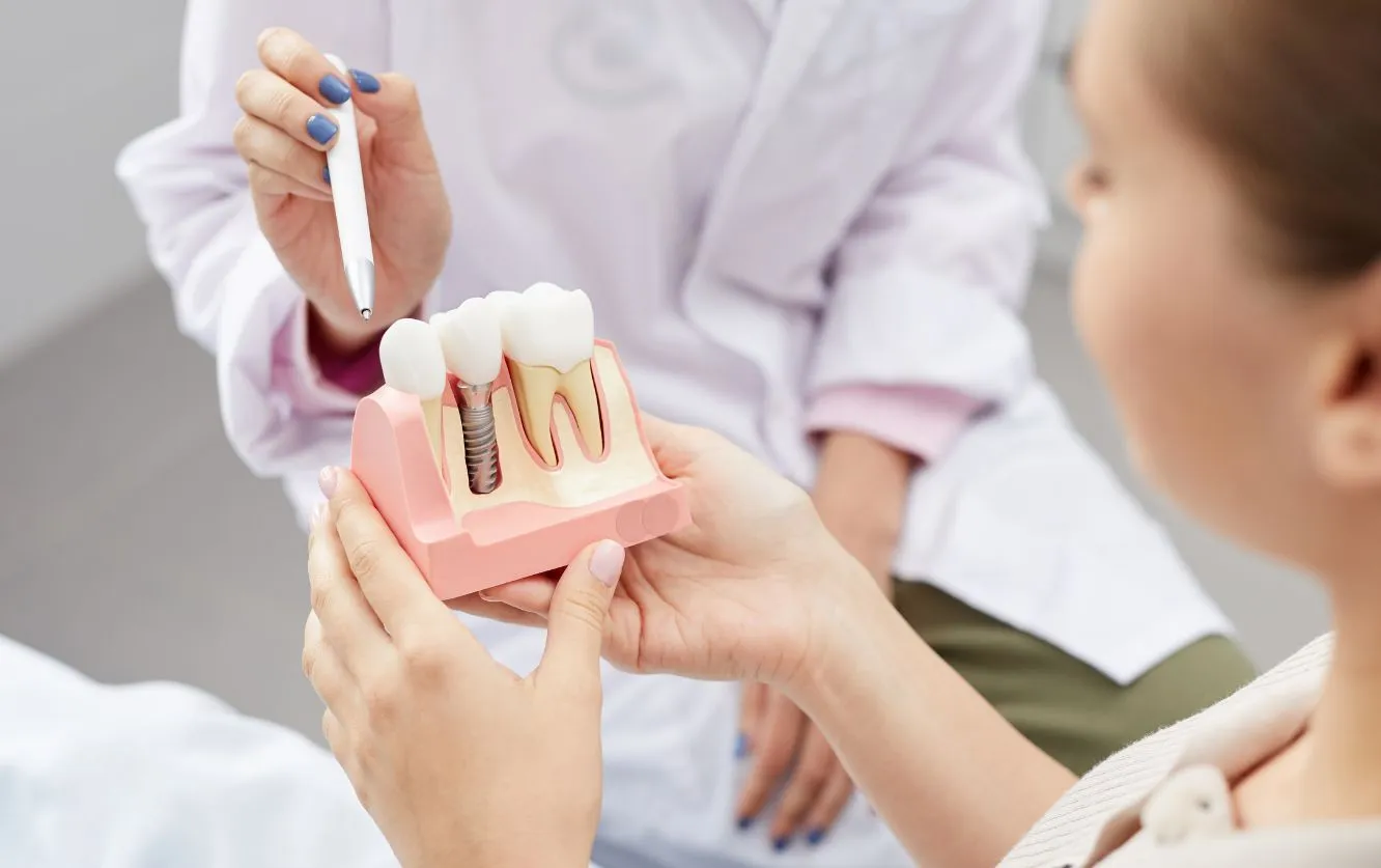 Elderly female patient attentively listening as a dentist uses a full arch denture model to explain removable or implant-supported denture options during a one-on-one restorative consultation in a modern operatory