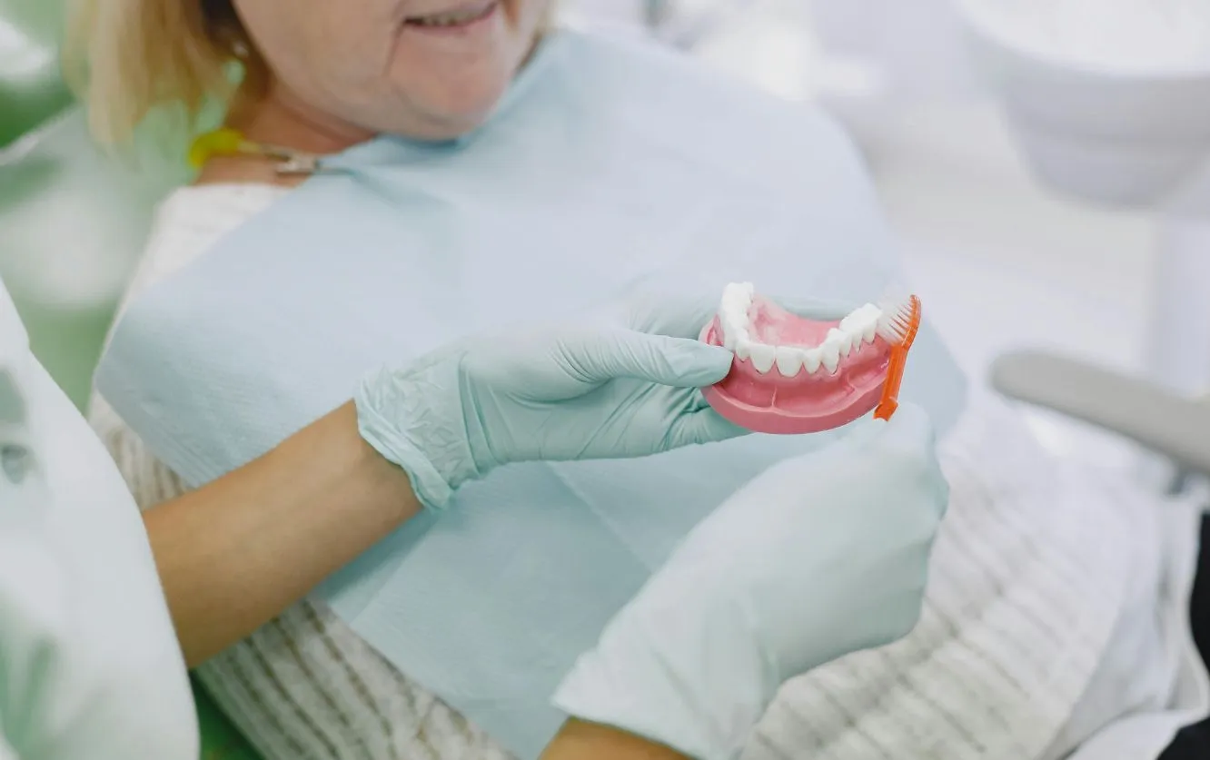 Gloved dental assistant holding a shade guide next to a patient’s teeth to select the perfect color match for dental crowns or veneers, during a cosmetic dentistry consultation focused on smile restoration and uniformity
