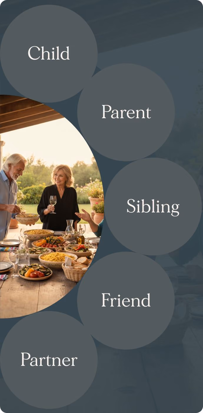Older adults enjoying outdoor meal with friends and family on a wooden table with various dishes.