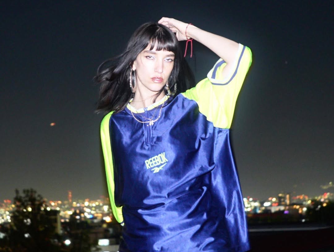 Murderith is light up but a bright flash with the Mexico City skyline in the background in this artist portrait.