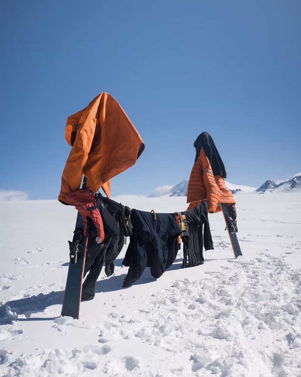 Wet climbing clothes drying on makeshift line in snowy mountain landscape