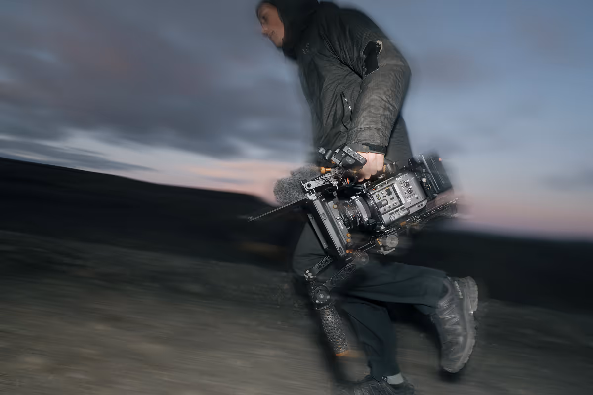 Cinematographer with stabilized camera rig filming at dusk in motion