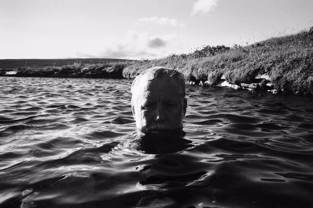 Geoff's head emerging from water near grassy shoreline
