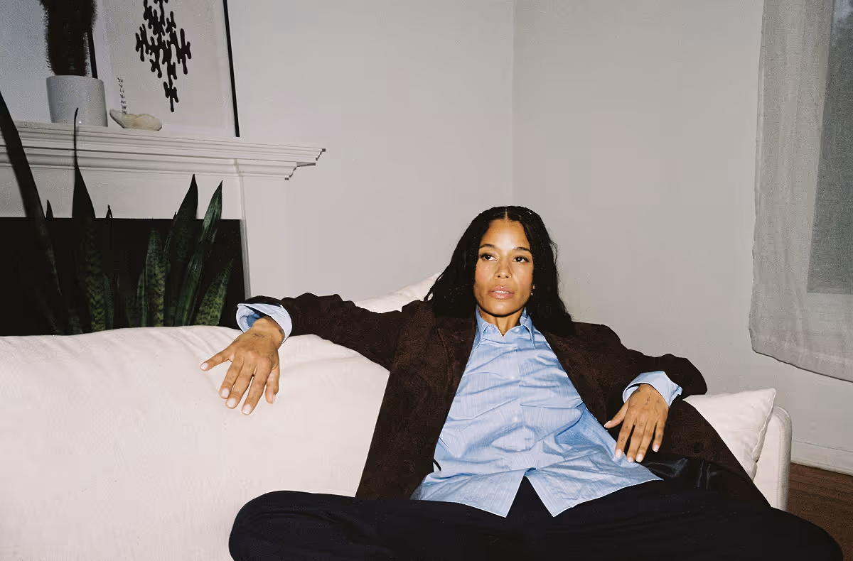Woman in brown blazer and blue shirt relaxing on white couch