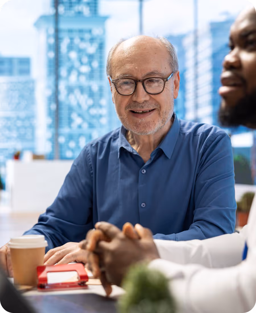 Photo of two professionals smiling and talking across a desk in a bright office.