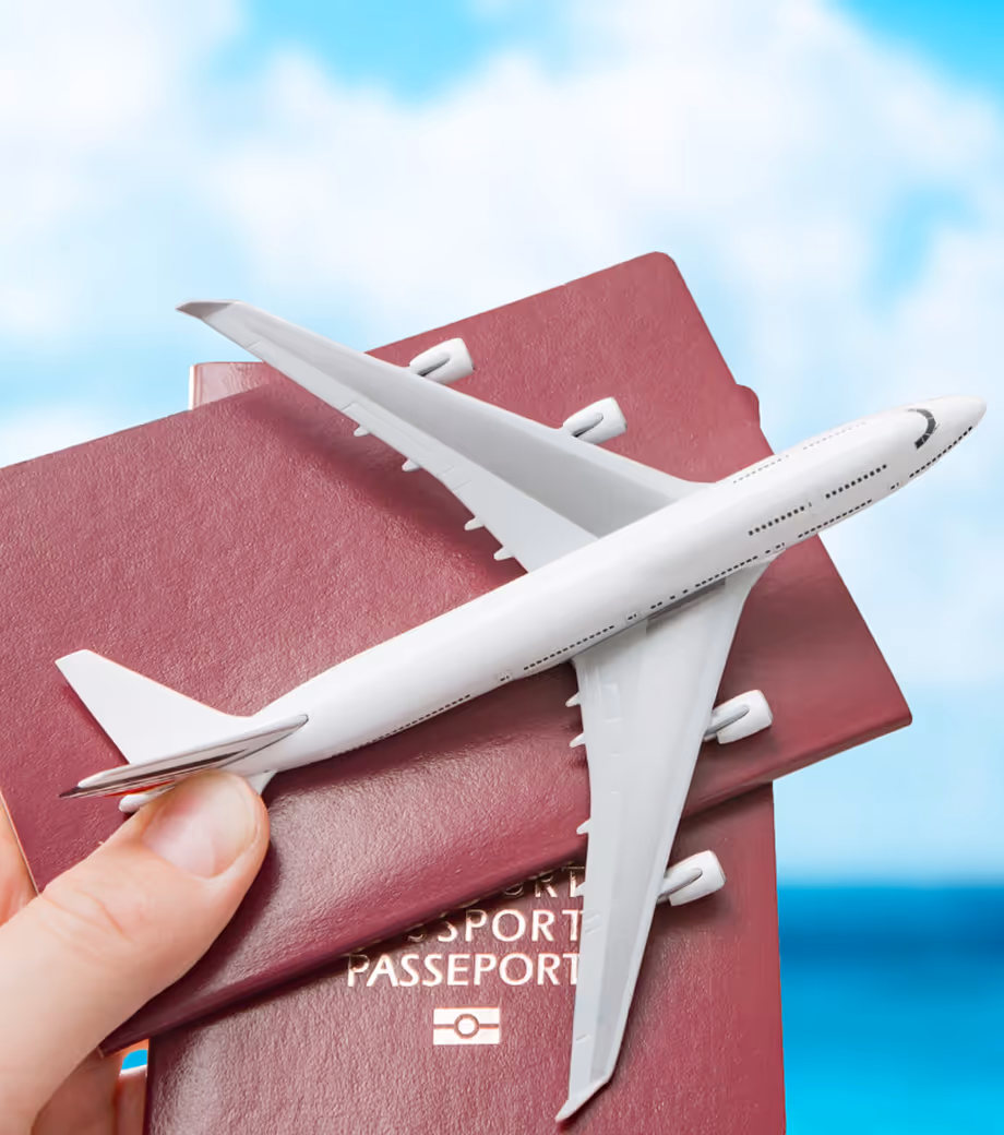 Close-up of a person holding passports with a model airplane resting on top.