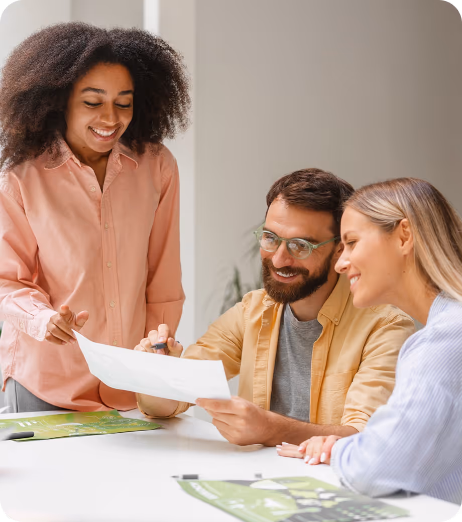 Smiling woman showing a document to a couple as they review paperwork together at a table.