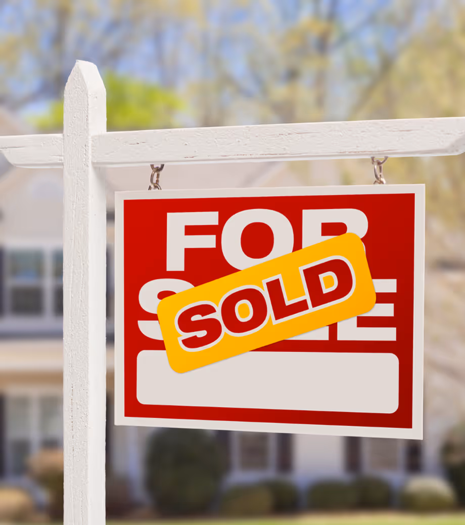 For Sale sign with a 'Sold' sticker placed on it in front of a house, symbolizing a completed property sale.