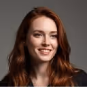 Smiling woman with long brown hair wearing a black top against a white background.