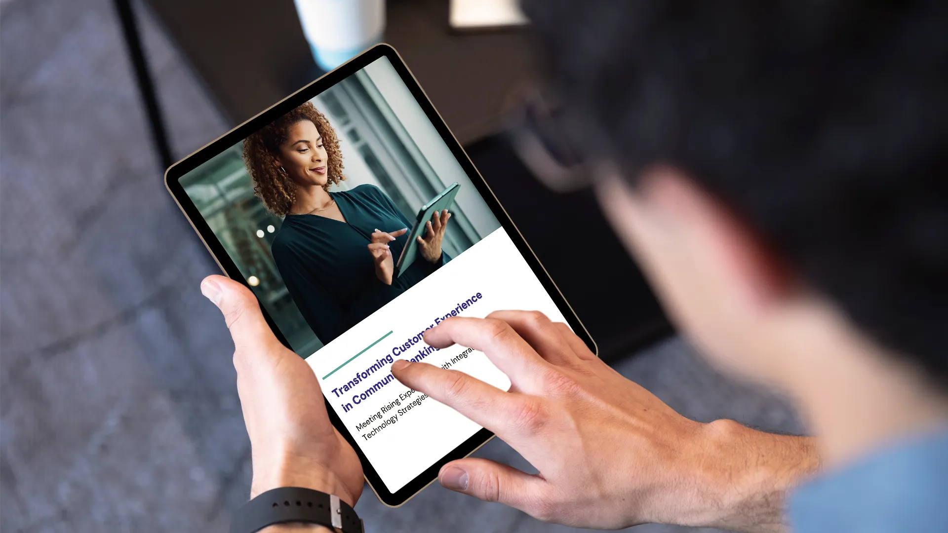 Person holding a tablet displaying a webpage with a woman using a tablet and the text 'Transforming Customer Experience in Community Banking'.