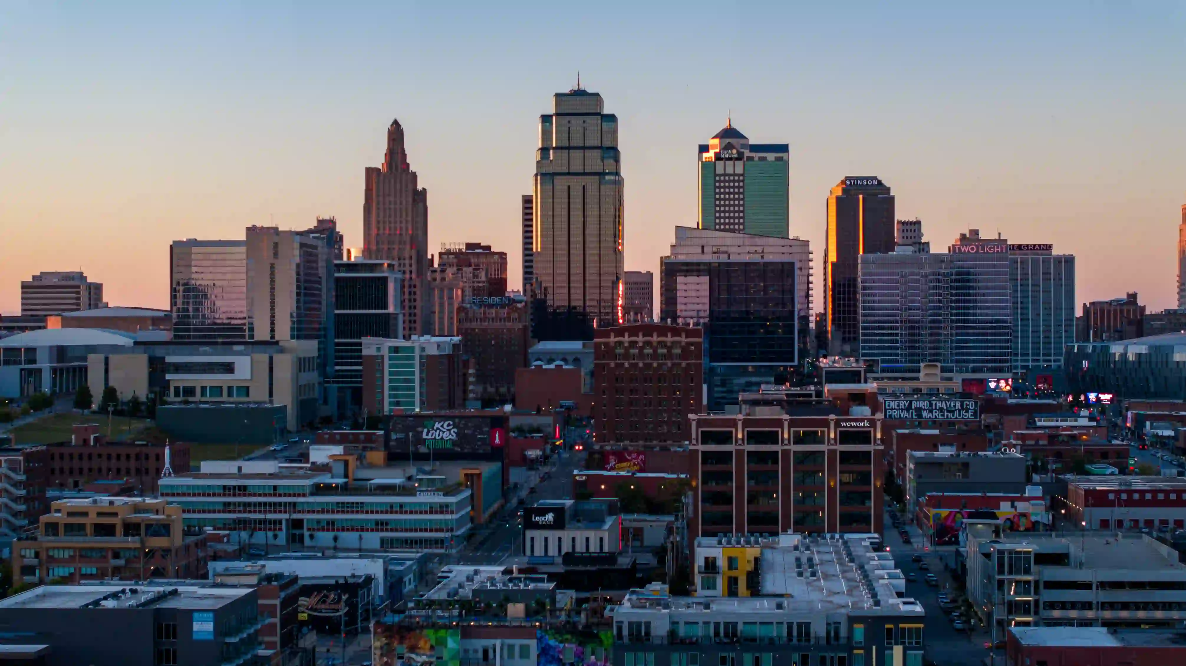 City skyline at sunset with tall modern buildings reflecting orange light.