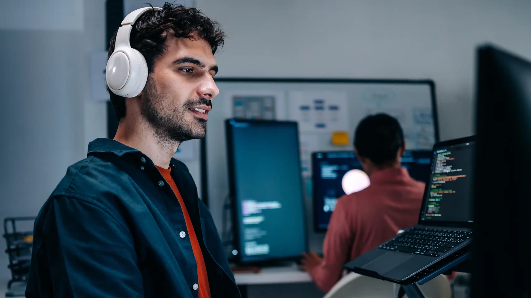 Developer wearing headphones coding on a computer in an office.