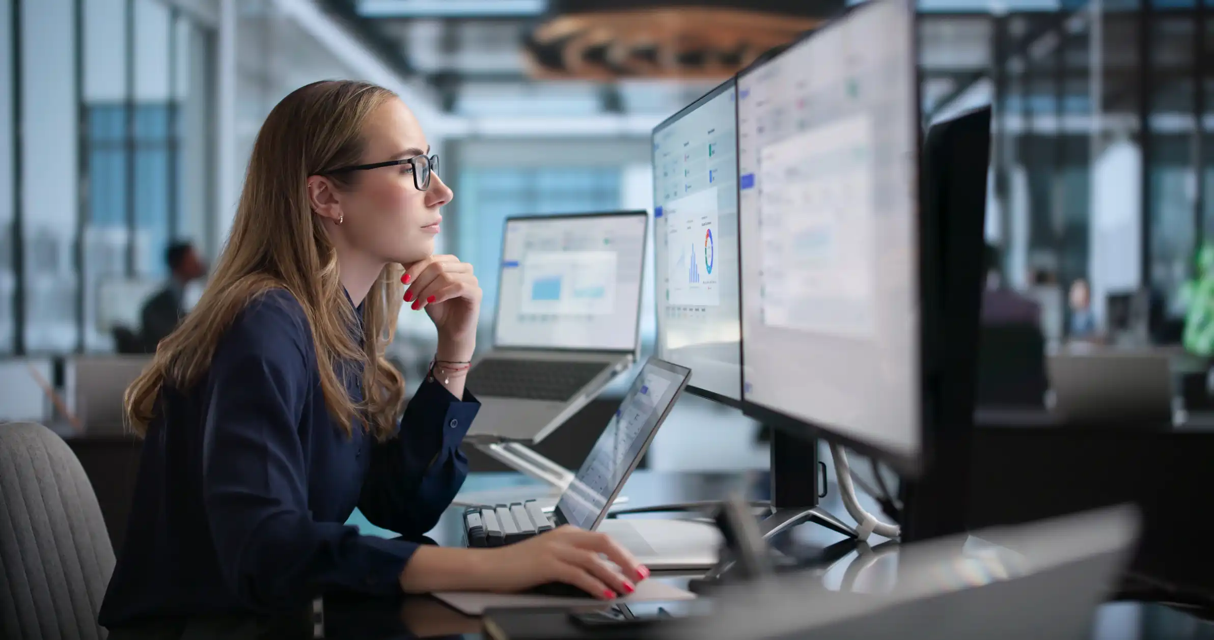 Professional monitoring enterprise software dashboards across multiple screens in a modern office, representing enterprise CX, system integration, and digital operations.