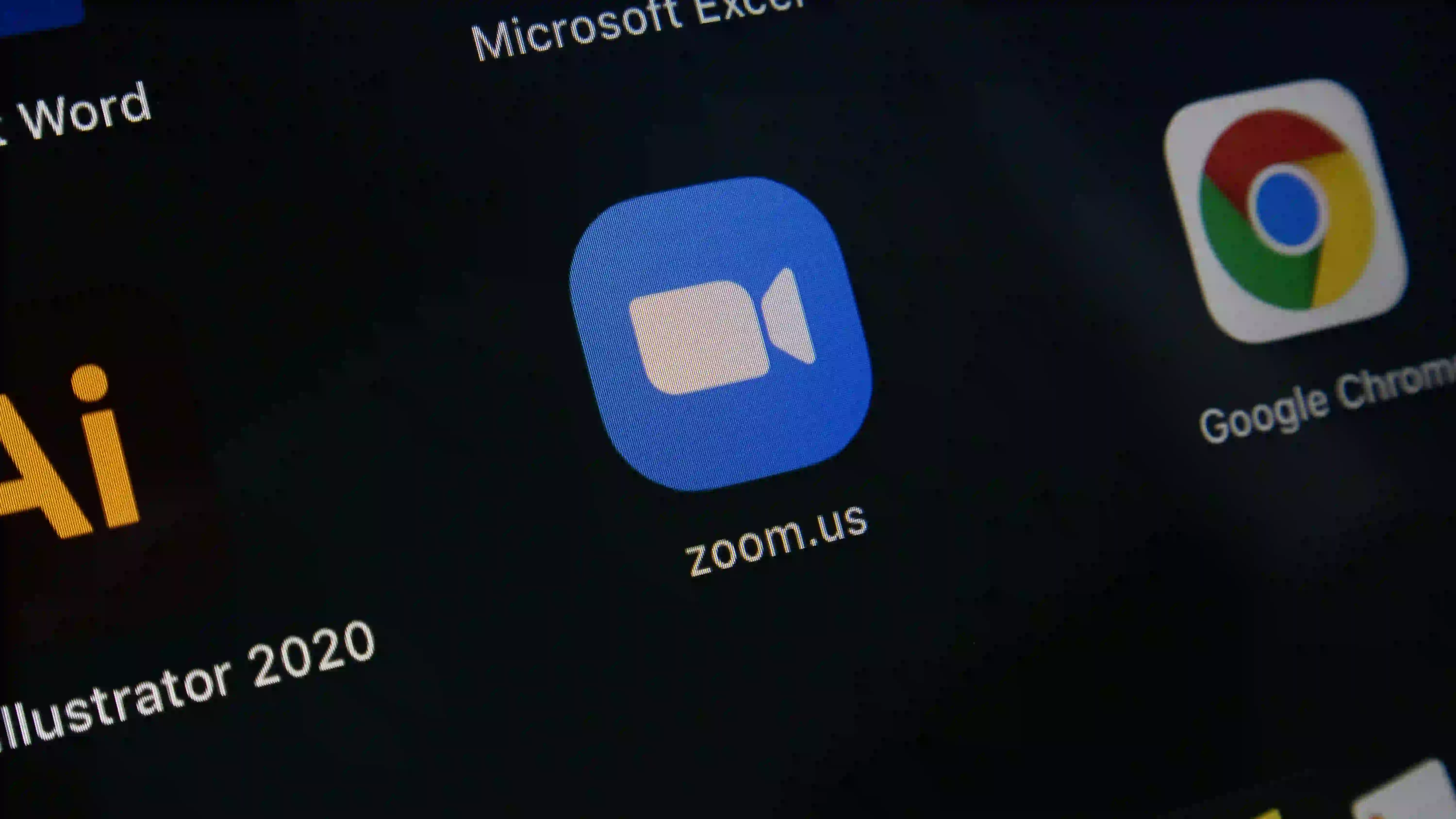 Close-up of a computer screen displaying the Zoom app icon alongside and other software icons on a desktop.