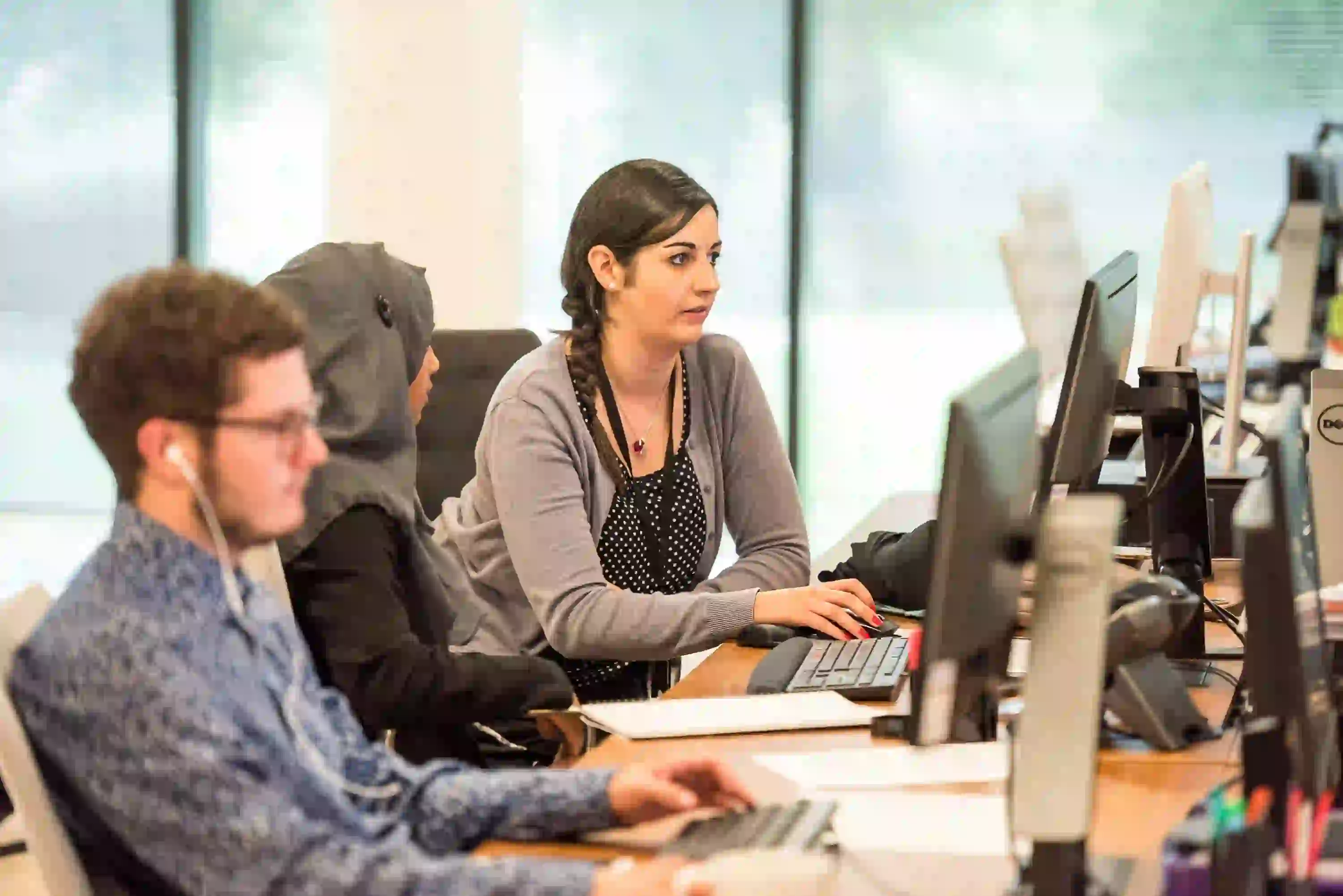 Office colleagues working together at computer workstations.