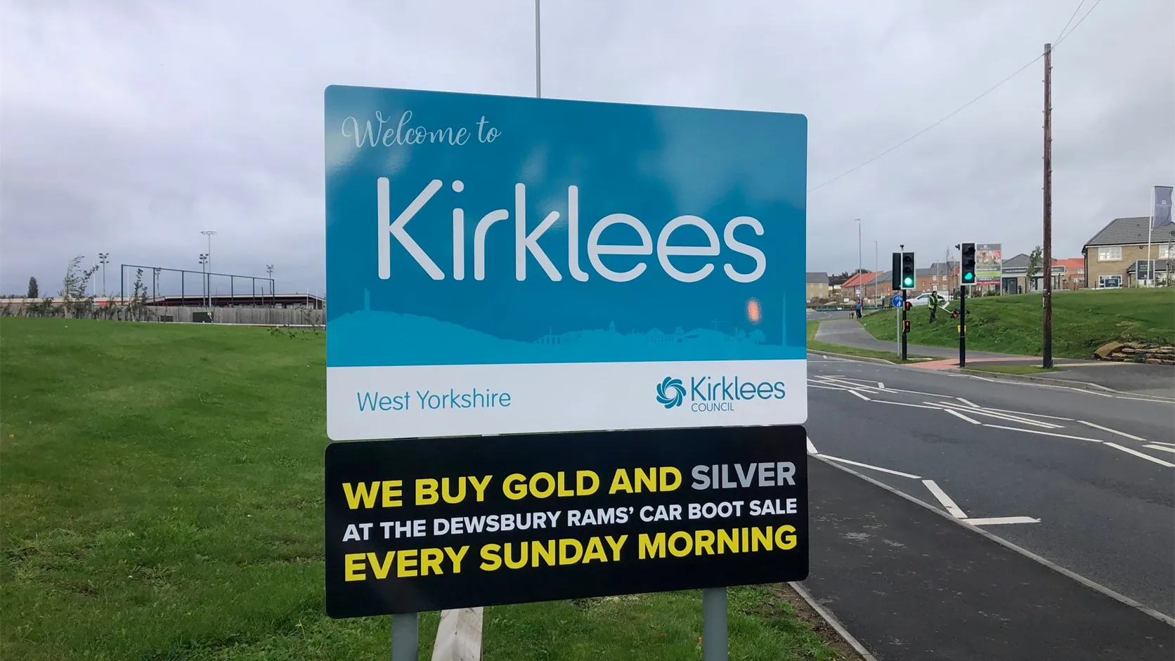 We Buy Gold advertising panel beneath the Welcome to Kirklees sign