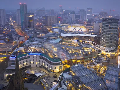 Birmingham city centre at dusk seen from above, with the Bullring, Rotunda and lit-up shopping area