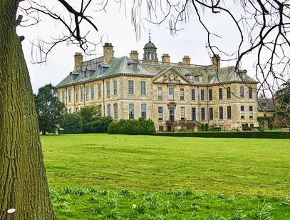 Large stately home with a slate roof and cupola seen across a wide lawn near Grantham