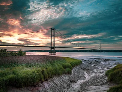 Humber Bridge at sunset with dramatic clouds over the estuary mudflats near Hull