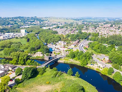 Aerial view of a river, road bridge and wooded valley with houses across Kirklees