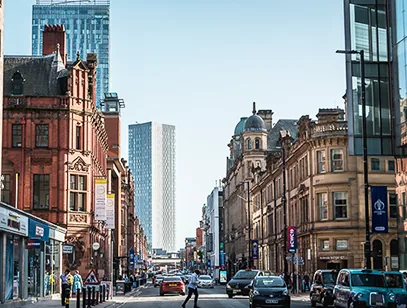 City street in Manchester lined with Victorian buildings and modern tower blocks