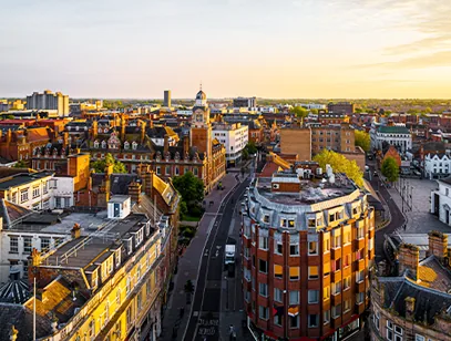 Aerial view of brick buildings and a clock tower in Leicester at golden hour