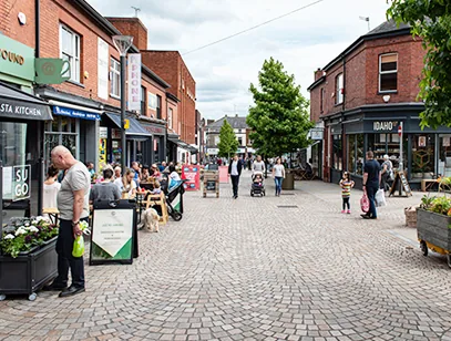 Pedestrianised cobbled street lined with red-brick shops and cafes in Macclesfield