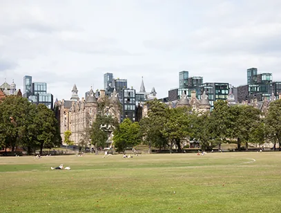 Edinburgh skyline of historic and modern buildings beyond an open grassy park, near Midlothian
