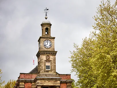 Clock tower of a red-brick and stone civic building against a grey sky in Newcastle-under-Lyme