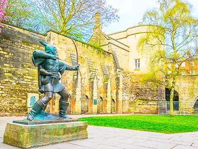 Robin Hood statue drawing his bow in front of the castle walls in Nottingham