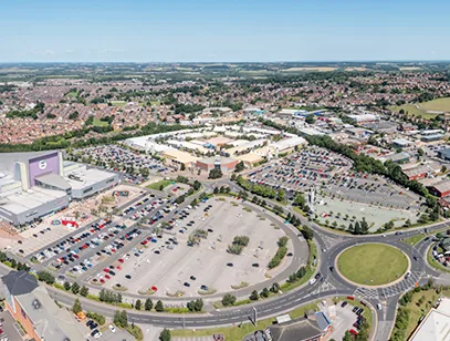 Aerial view of a retail park, car park and roundabout with housing beyond in Pontefract